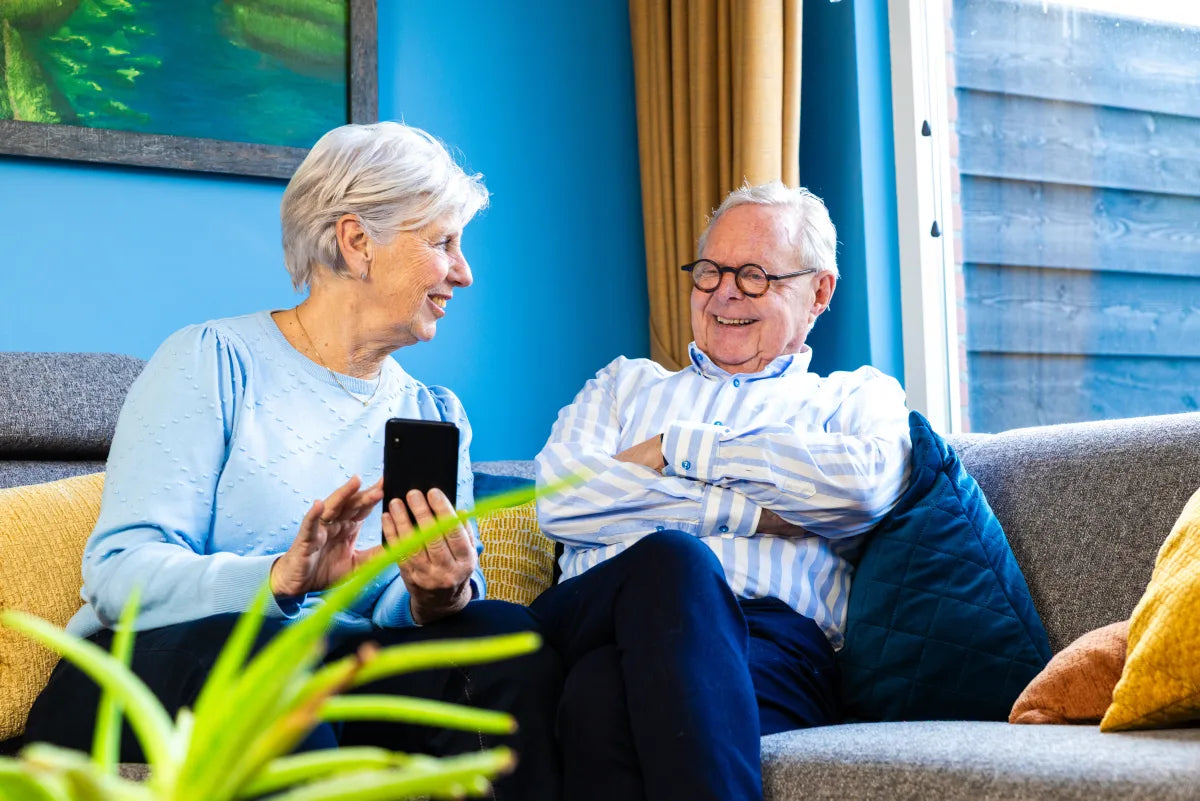 Older couple smiling together while holding a smartphone
